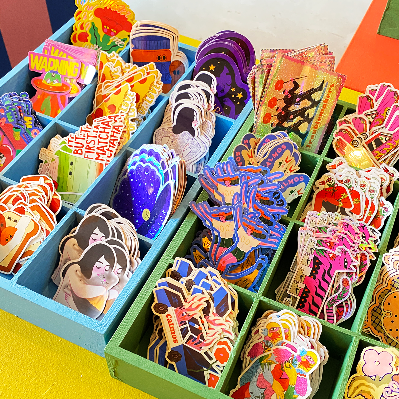 A variety of colorful, intricately designed stickers displayed in a blue organizer, each section showcasing unique graphic art.