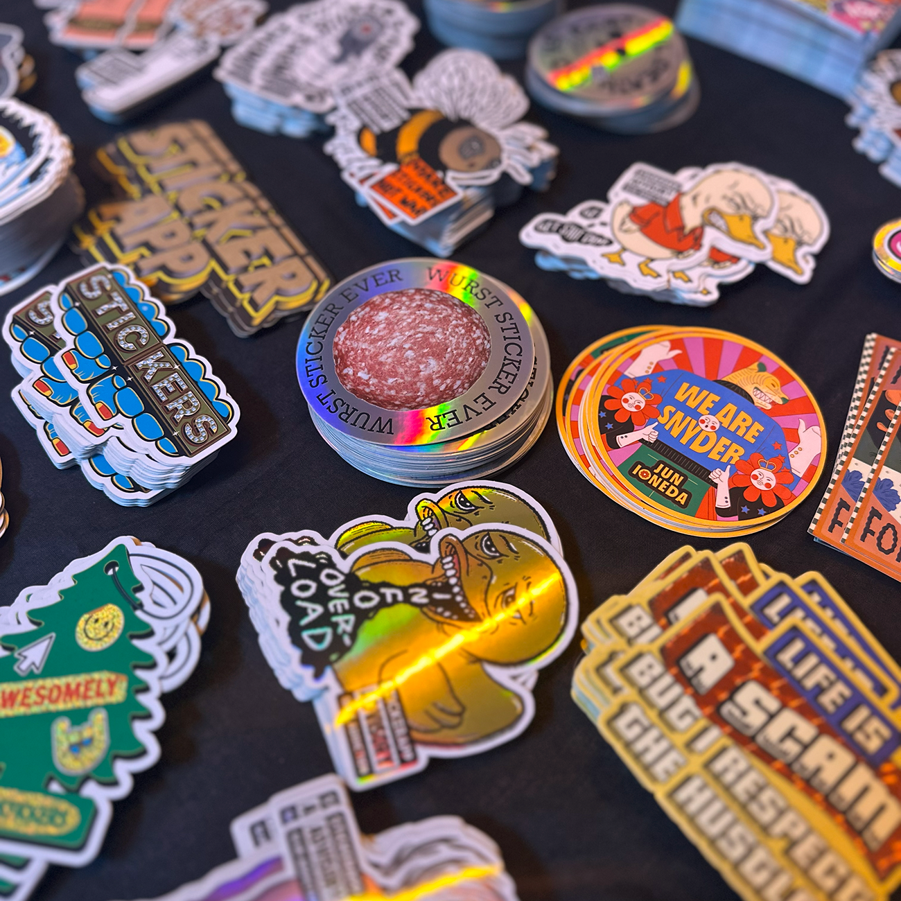 Die-cut stickers printed in various materials and sizes sitting on a dark table