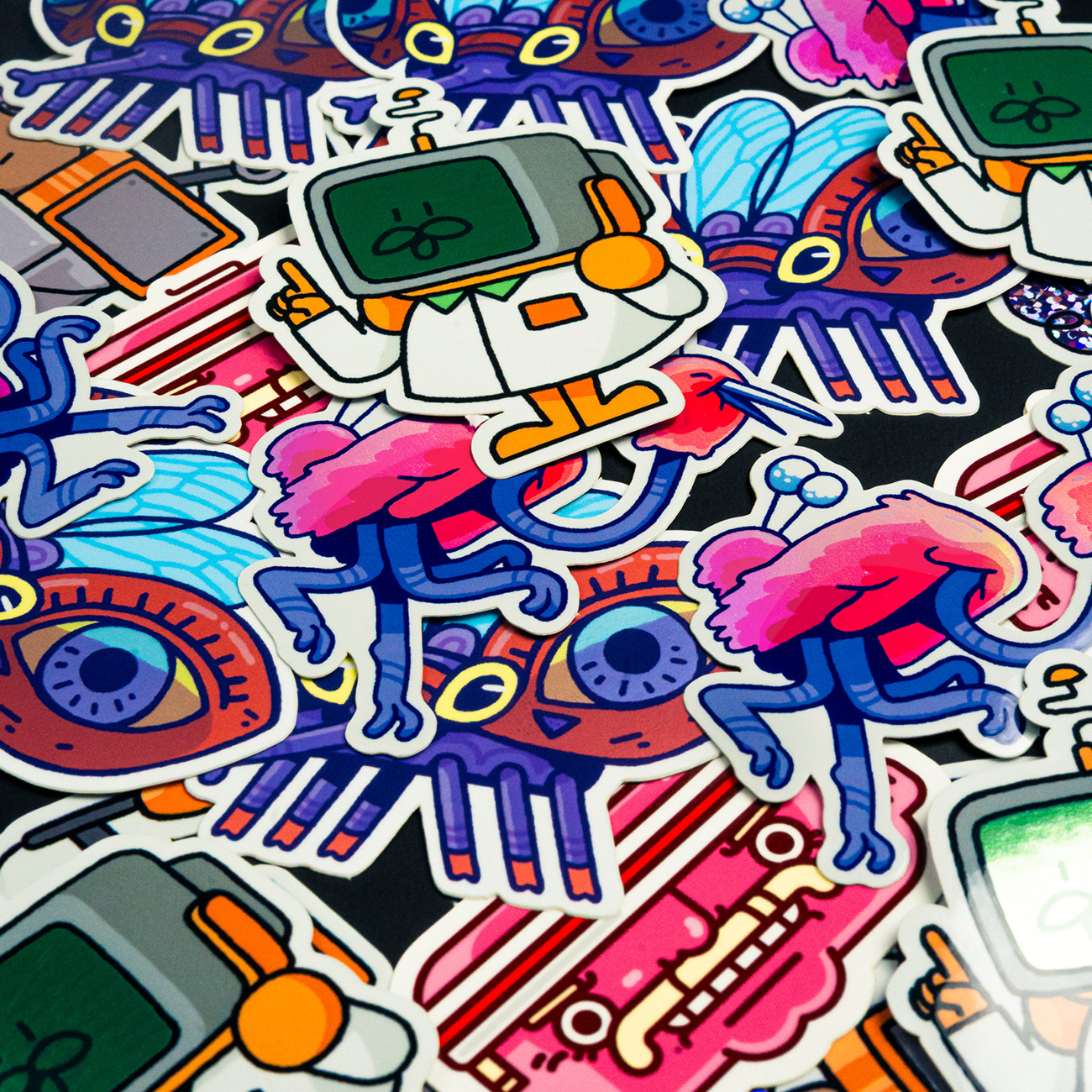 A variety of colorful die-cut stickers scattered on a table, printed on glitter and holographic material