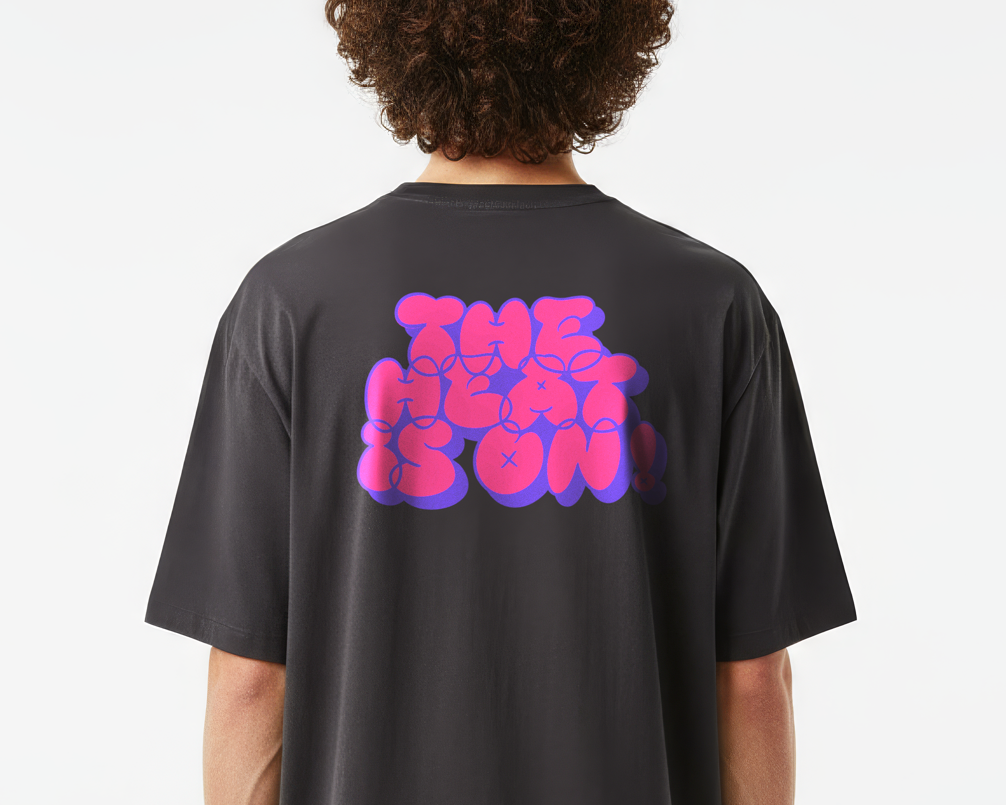 Person wearing a black T-shirt with vibrant pink and purple heat transfer saying "THE HEAT IS ON!" on the back.